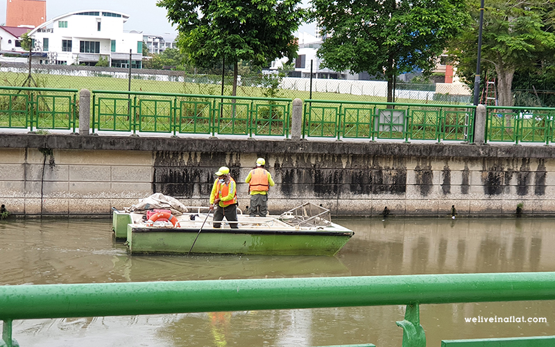 Two workers rowing a barge down the Geylang River.