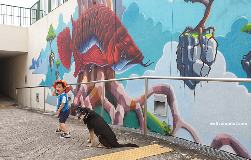 Boy and dog at Geylang Park Connector Underpass Wall Mural. "The Flight of the Arowana" by Didier Jaba Mathieu. This is part of the Arts in your Neighbourhood November 2020 programme.